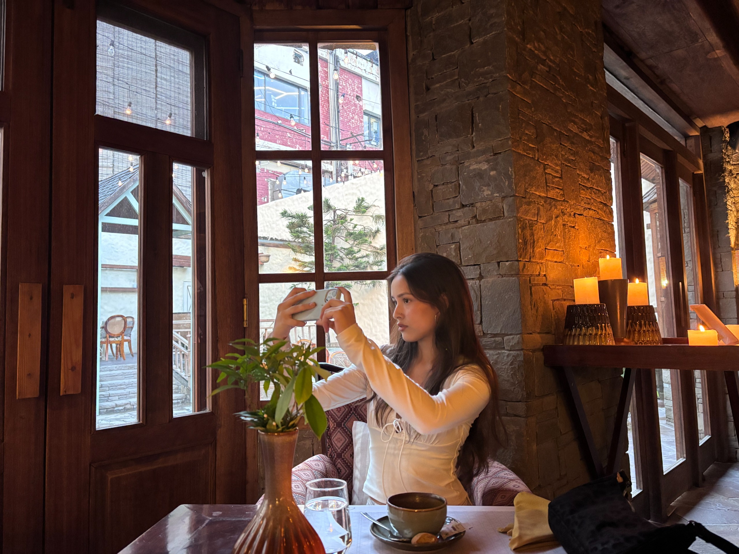 Shalika filming at a candlelit café window